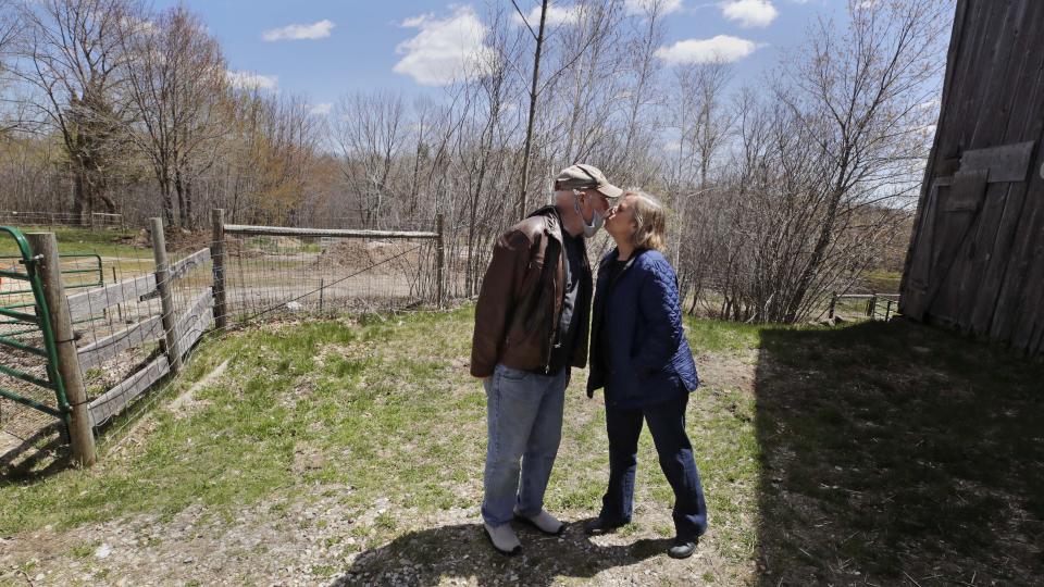 Emily DiPalma Aho, right, kisses her husband, George, as he leaves for a doctor's appointment, at their home in Jaffrey, N.H., Wednesday, May 13, 2020. Her father, Emilio DiPalma, stood guard as a 19-year-old U.S. Army infantryman at the Nuremberg Nazi war crimes trials. Emilio DiPalma died last month at the age of 93 after contracting the coronavirus at Holyoke Soldiers' Home in Massachusetts. (AP Photo/Charles Krupa)