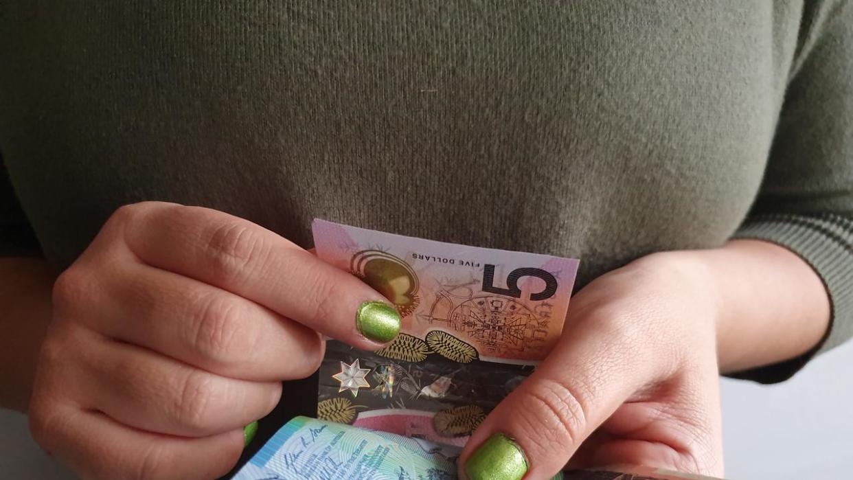 hands of a woman counting Australian money