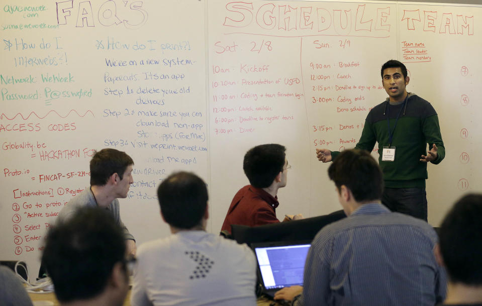 In this Saturday, Feb. 8, 2014 photo, Karim Bhalwani, manager of API Strategy and Sales at Yodlee Interactive, right, speaks to participants at the FinCapDev San Francisco Hackathon in San Francisco. A record 1,500 hackathons around the world are planned for this year, up from just a few dozen in 2010, and their focus is broadening from developing lucrative apps to solving problems with coding for an array of issues including dental, fashion, immigration, transgender and social justice. (AP Photo/Jeff Chiu)