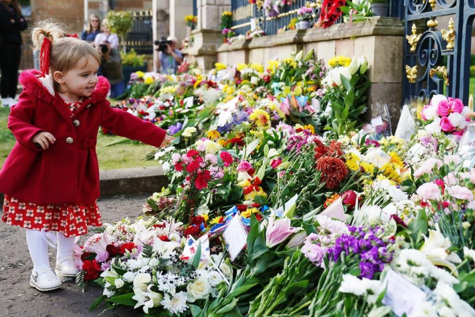 Abigail Glen (2), from Lisburn, lays flowers at the gates of Hillsborough Castle, Co. Down, following the death of Queen Elizabeth II on Thursday (Brian Lawless/PA) (PA Wire)