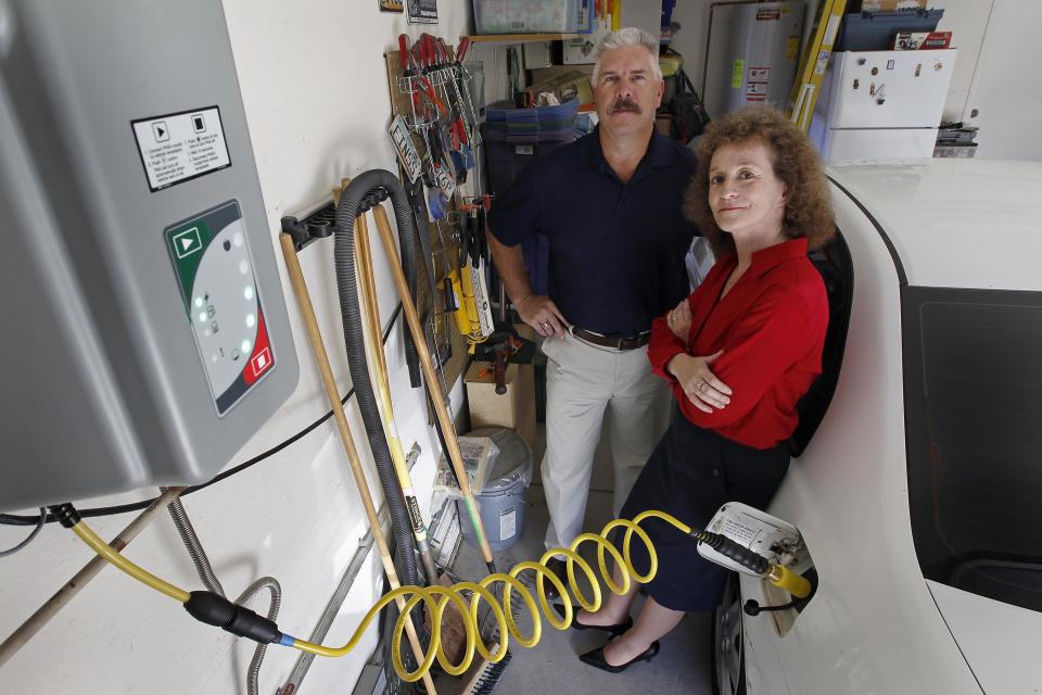 Connie and Travis Jones pose with their 2003 natural gas powered Honda Civic and natural gas home refueling station located on the garage wall of their home in Chandler, Arizona, October 3, 2013. (REUTERS/Ralph D. Freso)