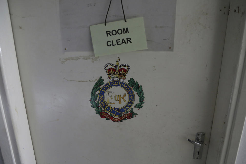 In this Friday, April 19, 2019, photo, an insignia of the royal engineers and a "room clear" sign hang on a door of a room at the Ledra Palace hotel inside the U.N. buffer zone in the divided capital Nicosia, Cyprus. This grand hotel still manages to hold onto a flicker of its old majesty despite the mortal shell craters and bullet holes scarring its sandstone facade. Amid war in the summer of 1974 that cleaved Cyprus along ethnic lines, United Nations peacekeepers took over the Ledra Palace Hotel and instantly turned it into an emblem of the east Mediterranean island nation's division. (AP Photo/Petros Karadjias)