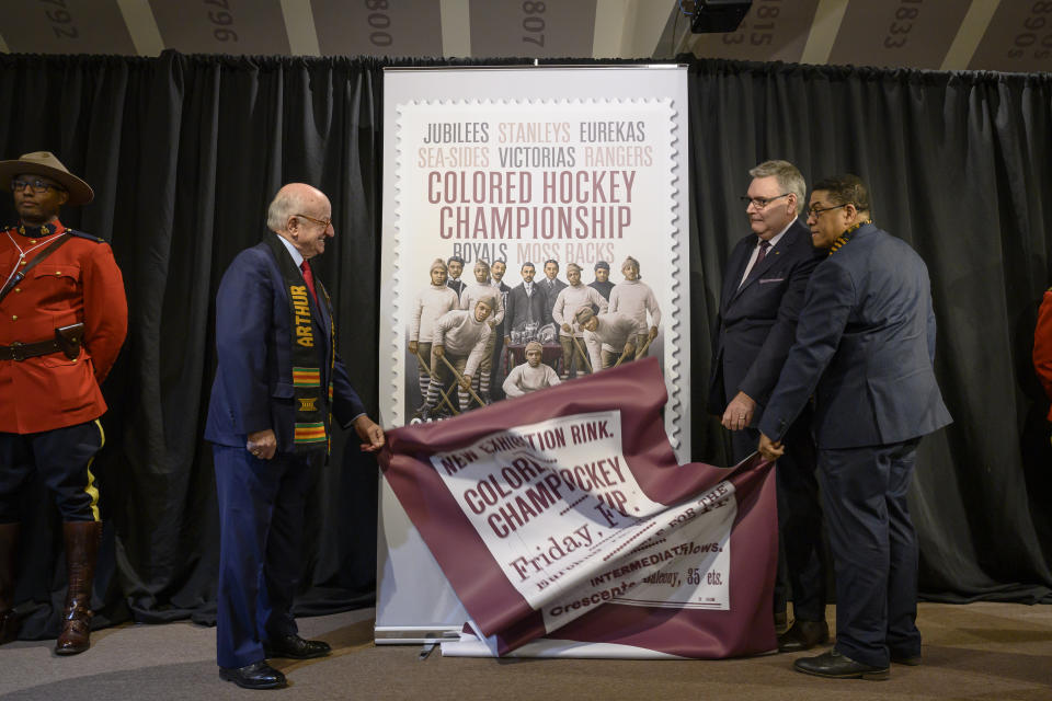 From left, Arthur J. LeBlanc, Lt. Gov. of Nova Scotia, Doug Ettinger, President and CEO of Canada Post, and Craig Smith, President of The Black Cultural Society, unveil Canada Post's stamp honouring the Colored Hockey Championship and the all-Black hockey teams in the Maritimes between 1895 and the early 1930s during an event at the Black Cultural Center in Halifax, Nova Scotia, Thursday, Jan. 23, 2020. (Darren Calabrese/The Canadian Press via AP)