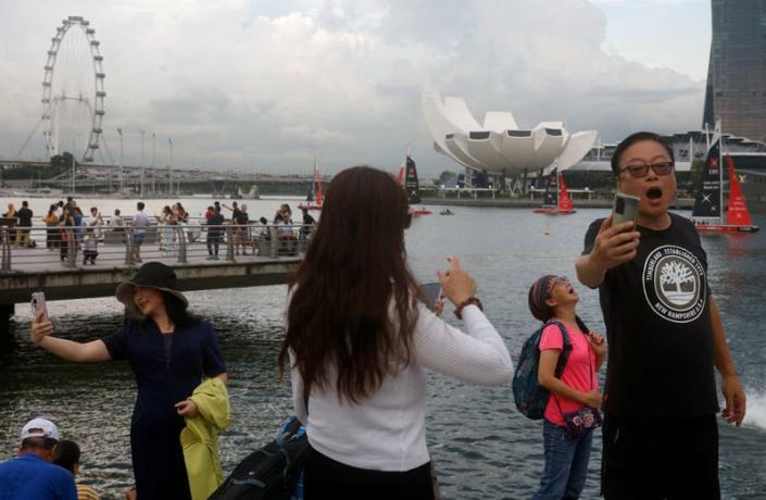 FILE PHOTO: Chinese tourists pose for photos with the Merlion statue at Marina Bay in Singapore