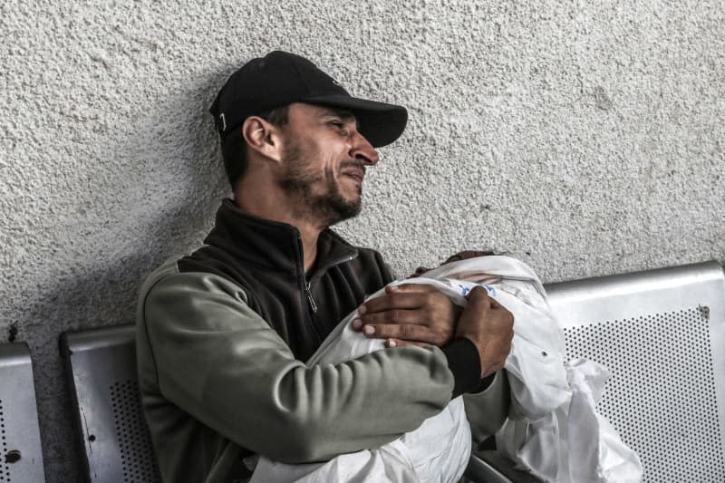 A Palestinian embraces the body of a child, where nine members of the Abu Radwan family were killed following an Israeli air strike. Abed Rahim Khatib/dpa