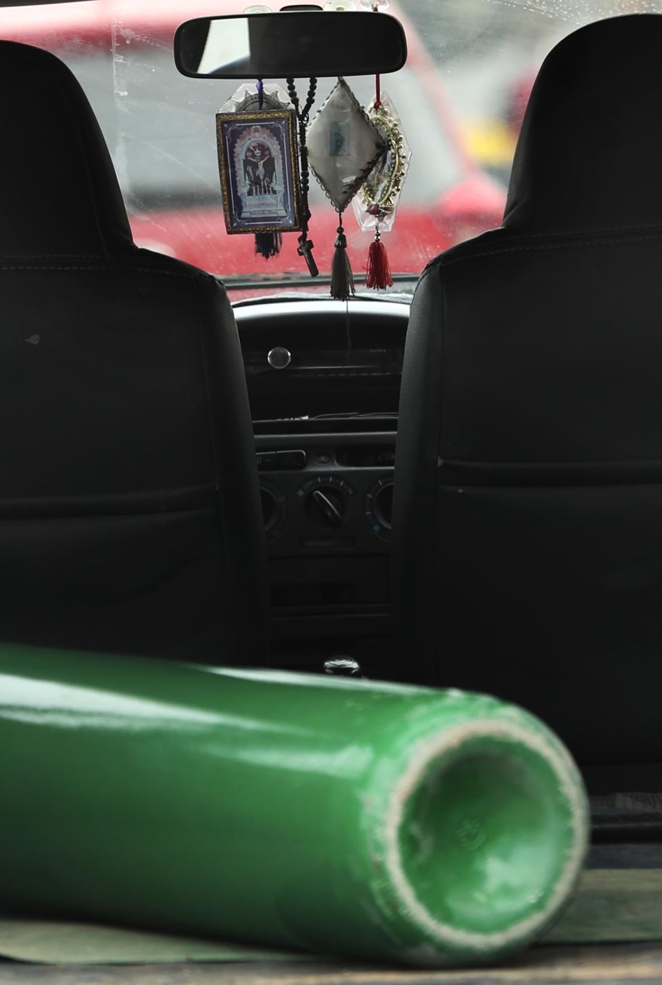 An empty oxygen tank sits in a car featuring iconic images of "The Lord of Miracles" as the car's driver asks an oxygen refill store if there's enough supply to get in line, in the Villa El Salvador shantytown of Lima, Peru, Thursday, Jan. 21, 2021, amid the COVID-19 pandemic. The driver was turned away because the store had already assigned the day's oxygen maximum amount of refills, 20, to people who arrived earlier. (AP Photo/Martin Mejia)