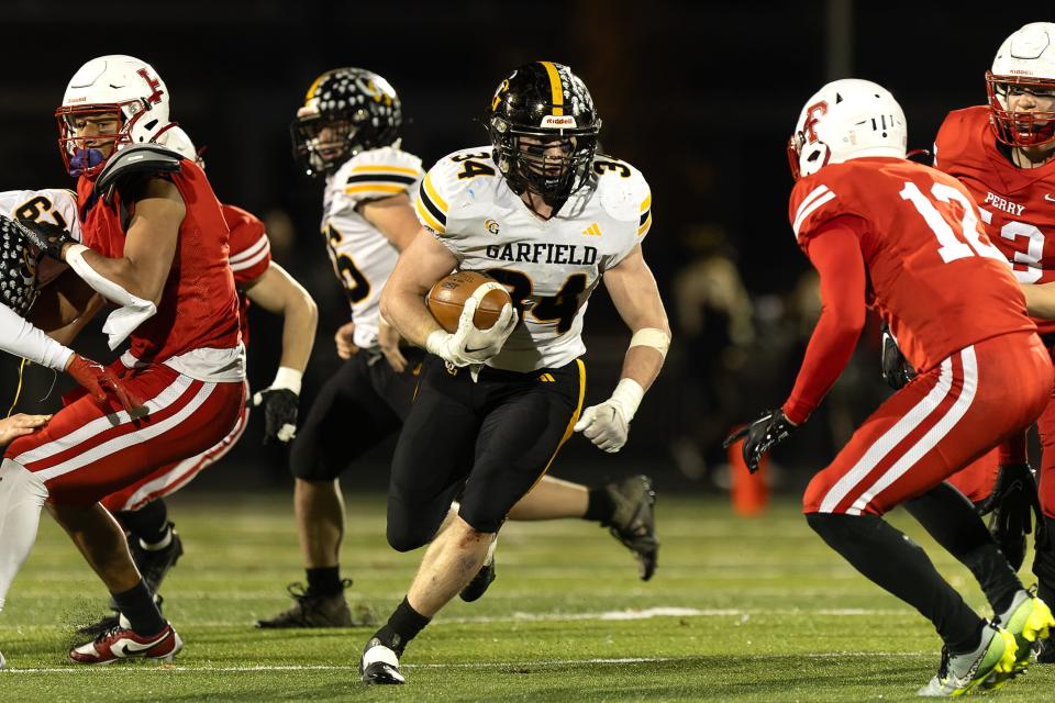 Garfield running back Keegan Sell breaks through the line during an OHSAA regional semifinal playoff game against Perry High School Friday, Nov. 10, 2023 in Maple Heights, OH.