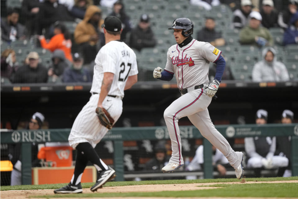 Atlanta Braves' Austin Riley, right, heads home scoring on Chicago White Sox relief pitcher Bryan Shaw's wild pitch, left, during the fifth inning of a baseball game Monday, April 1, 2024, in Chicago. (AP Photo/Charles Rex Arbogast)