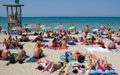 Tourists sunbath on Palma's beach  - Credit: JAIME REINA / AFP