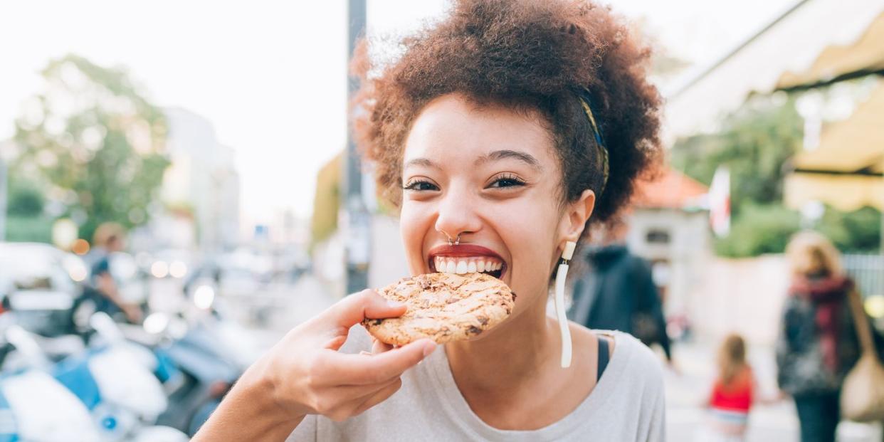 young woman eating cookie at outdoor cafe