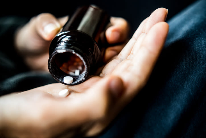 Close-up of a person's hands dispensing a pill from a bottle into their palm