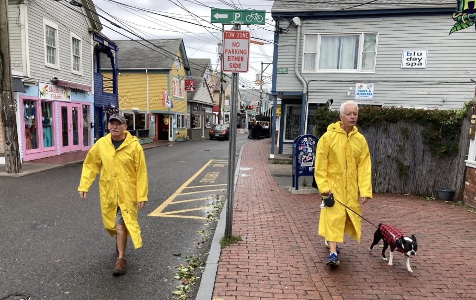 Provincetown residents David Geiger (left) and John Lamb, and their dog Cooper, take a walk east Saturday morning on Commercial Street in Provincetown. Hurricane Lee passed east of Cape Cod overnight, leaving behind wet pavement, light rain and strewn leaves and branches on the streets. Winds were about 40 miles per hour at 8:30 a.m. Saturday morning.