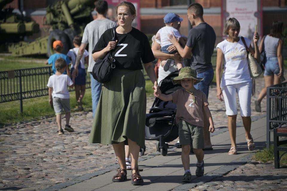 A woman and her child wear T-shirts with the letter Z, which has become a symbol of support for the Russian military, as they walk on the grounds of the Artillery Museum in St. Petersburg, Russia, in August 2022. (AP Photo/Dmitri Lovetsky)