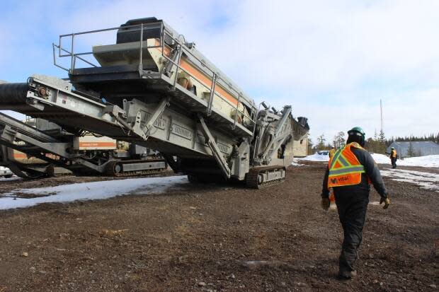 Kyle Bayha, an employee at the Nechalacho rare earths mine demonstration project, pictured on Thursday. He walks past a crusher that'll be used to break down ore. (Liny Lamberink/CBC North - image credit)