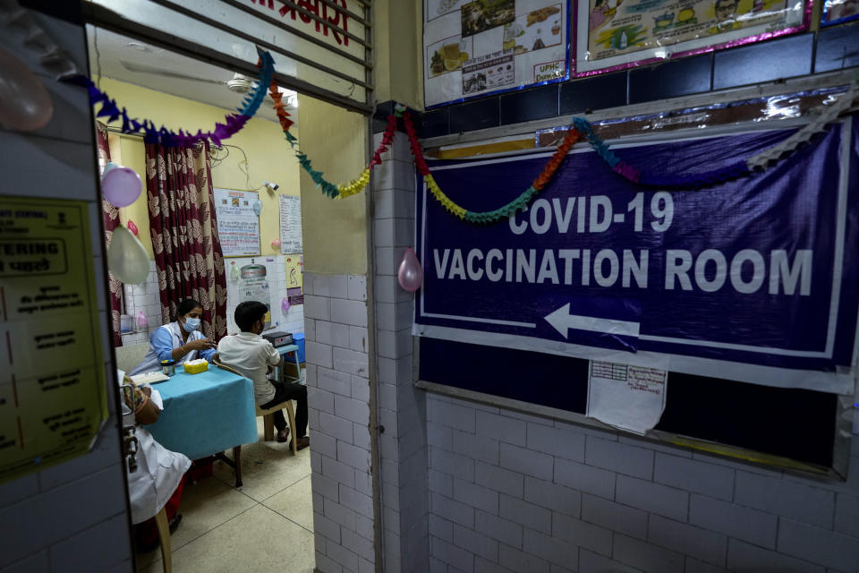 A health worker inoculates a man at a government hospital in New Delhi, India, Thursday, Oct. 21, 2021. India has administered 1 billion doses of COVID-19 vaccine, passing a milestone for the South Asian country where the delta variant fueled its first crushing surge this year. (AP Photo/Manish Swarup)