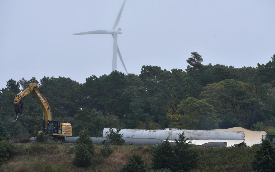 FALMOUTH  10/05/22  Demolition crews rip apart the Falmouth Wind 1 turbine which was toppled last week as it's twin Wind 2 was brought to the ground exactly at 10 am on Wednesday.  The wind turbine in the background is located on Joint Base Cape Cod and is not one of Falmouth's.
Cape Cod Times/Steve Heaslip