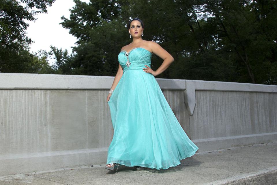 This product image released by Sydney’s Closet shows a woman modeling a plus size prom dress. Clothes shopping for plus-size teens can be frustrating in general, but shopping for a dream prom dress can be a tear-inducing, hair-pulling morass of bad design and few options _ especially for girls who want a dress that hugs the body instead of tenting it. (AP Photo/Sydney’s Closet)