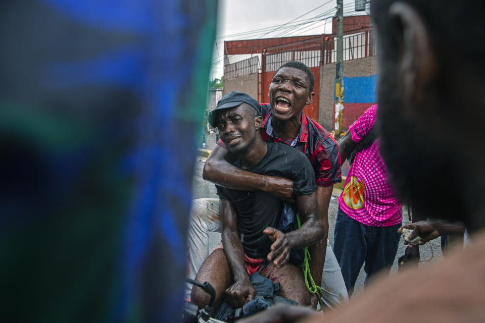 A protester who was hit in the leg by police fire is helped onto a motorcycle to be taken to the hospital, as police clash with demonstrators in Port-au-Prince, Haiti, Sept. 30, 2019. The image was part of a series of photographs by Associated Press photographers which was named a finalist for the 2020 Pulitzer Prize for Breaking News Photography. (AP Photo/Rebecca Blackwell)