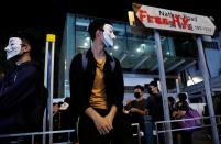 Protesters wearing Guy Fawkes masks stand near a road sign as they attend an anti-government demonstration in Hong Kong