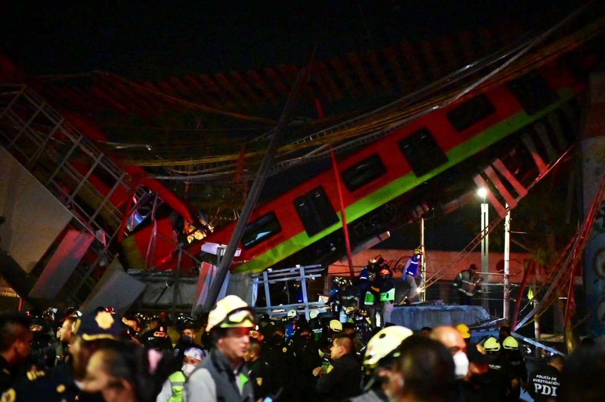 <p>Rescue workers gather at the site of a metro train accident after an overpass for a metro partially collapsed in Mexico City on Monday (3 May)</p> (AFP/Getty)