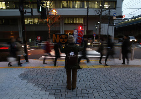 A protester holds banners towards the headquarters of Tokyo Electric Power Co (TEPCO), the operator of the tsunami-crippled Fukushima Daiichi nuclear plant, during an anti-nuclear rally, a day before the five-year anniversary of the disaster, in Tokyo, Japan, March 10, 2016. REUTERS/Yuya Shino