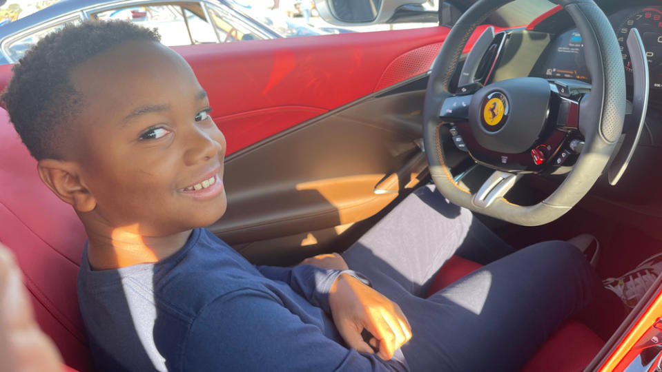 Kyrie Hosier, a ten-year-old car enthusiast, sits in a Ferrari Roma.