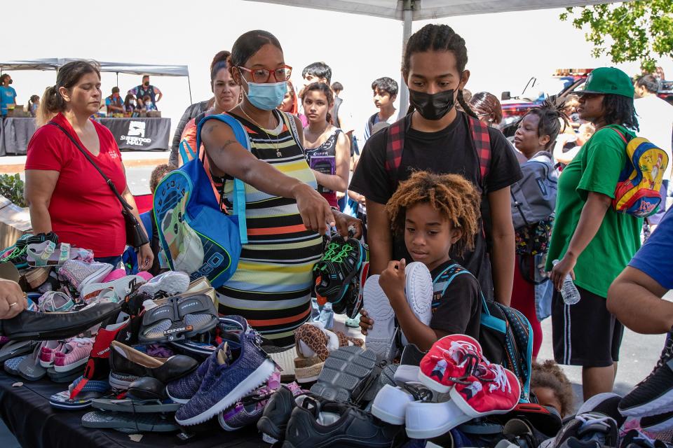 Brandie McDonald, of Stockton points out shoes to her sons during the Stockton 209 Cares annual backpack giveaway on Saturday, July 16, 2022, at Sherwood Mall in Stockton. Walmart donated three truckloads of shoes, according to Nancy Lamb, Stockton 209 Cares founder and president. (SARA NEVIS/FOR THE RECORD)