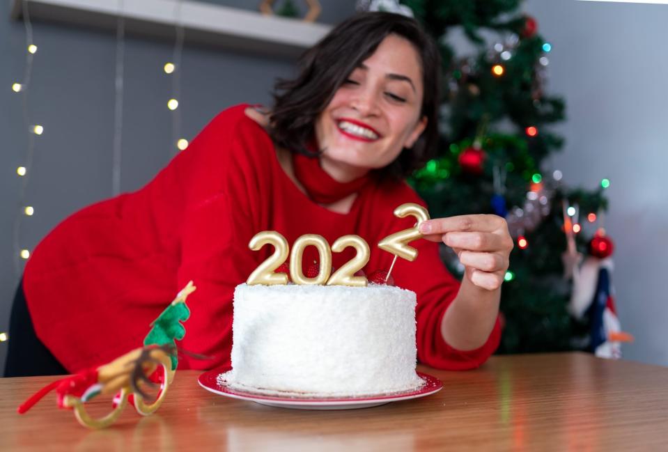 Happy Woman Celebrating Christmas At Home, Holding Cake With Candles Shaped As Numbers 2022