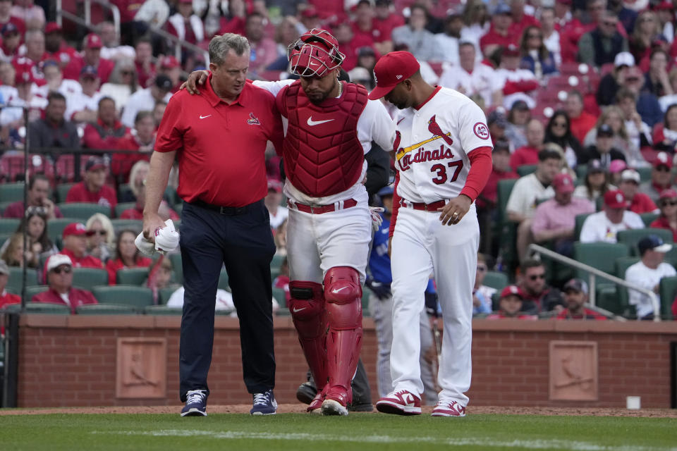 St. Louis Cardinals catcher Willson Contreras, center, leaves a baseball game with the help of trainer Chris Conroy and manager Oliver Marmol (37) after being injured during the eighth inning on opening day against the Toronto Blue Jays Thursday, March 30, 2023, in St. Louis. (AP Photo/Jeff Roberson)