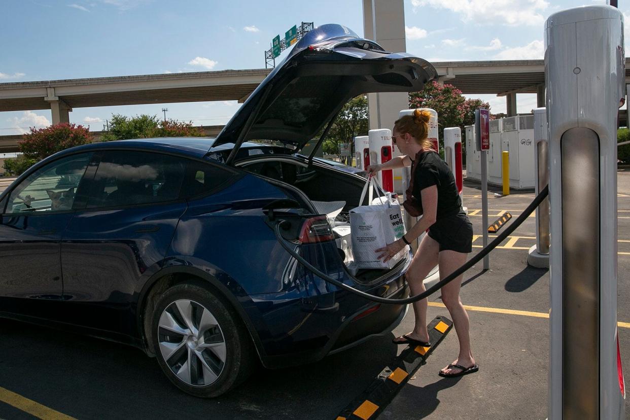 A woman charges her Tesla at an electric vehicle charging station in Austin, June 30, 2022.