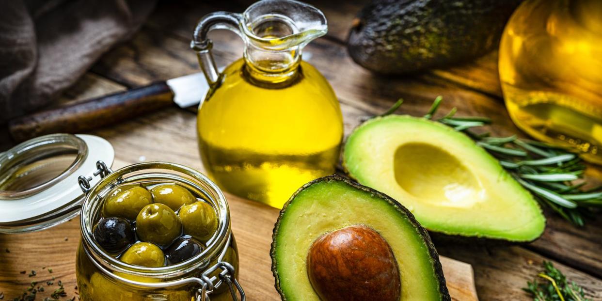 vegan food high angle view of extra virgin olive oil and avocado oil shot on rustic wooden table sliced organic avocado and a glass container with olives complete the composition predominant colors are yellow and green high resolution 42mp studio digital capture taken with sony a7rii and sony fe 90mm f28 macro g oss lens