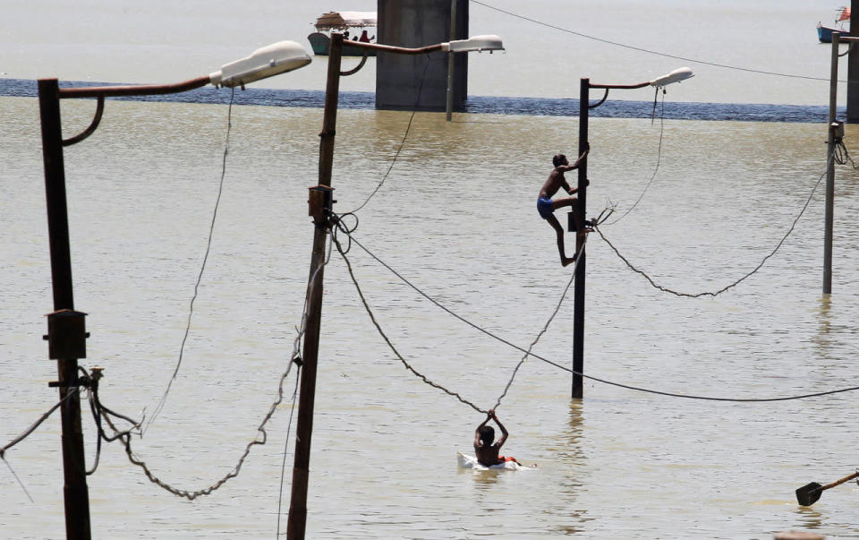 <p>A boy climbs a partially submerged electric pole as he plays with others on the flooded banks of Ganga river, in Allahabad, India, August 21, 2016 (REUTERS/Jitendra Prakash)</p>