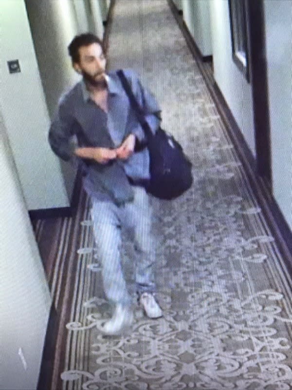 Justin Mullis walks through a carpeted corridor holding a bag. 