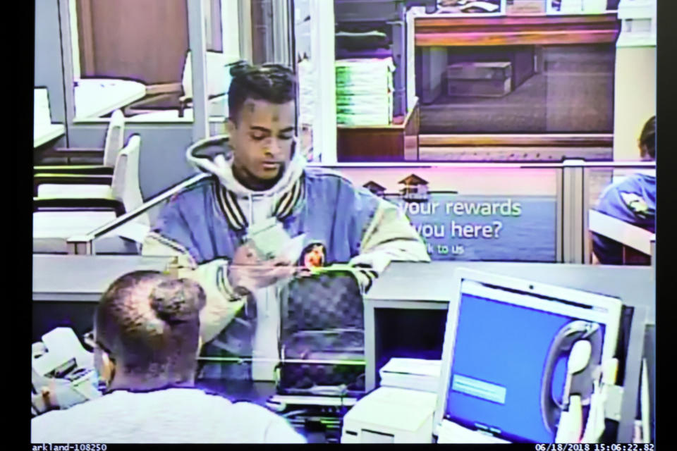 In this Bank of America surveillance video image, Jahseh Onfroy, 20, whose stage name was XXXTentacion, places $50,000 he withdrew from his account in a Louis Vuitton bag at a Bank of America branch, on June 18, 2018, in a video that was shown during the murder trial of defendants Michael Boatwright, Trayvon Newsome and Dedrick Williams at the Broward County Courthouse in Fort Lauderdale, Fla., Tuesday, Feb. 7, 2023. XXXTentacion was robbed of the money and killed outside Riva Motorsports in Pompano Beach in 2018. (Amy Beth Bennett/South Florida Sun-Sentinel via AP, Pool)