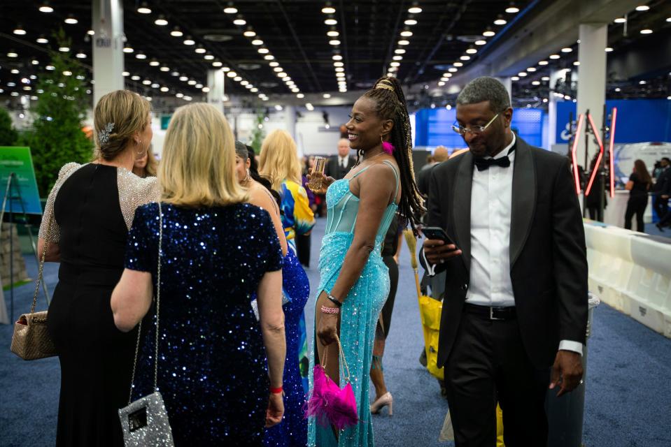 Detroit resident Gourmay Brice, center, talks with people about her gown during the 2023 North American International Detroit Auto Show Charity Preview at Huntington Place in Detroit on Friday, September 15, 2023.