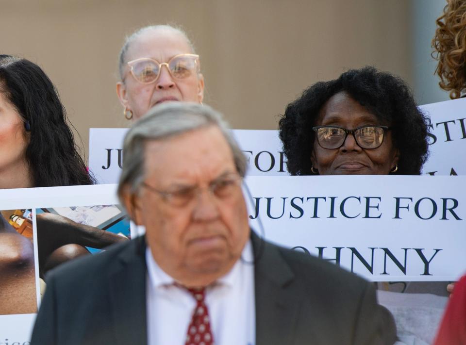 Emma Holmes, right, holds a sign during a press conference at the Thad Cochran Federal Courthouse in Jackson on Wednesday, Feb. 14, 2024. Attorney George "Boo" Hollowell stands in front of her.