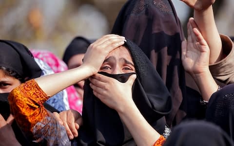 Women wail as they watch the body of Zubair Ahmed Turay, a suspected militant, being carried away during his funeral procession - Credit: Reuters