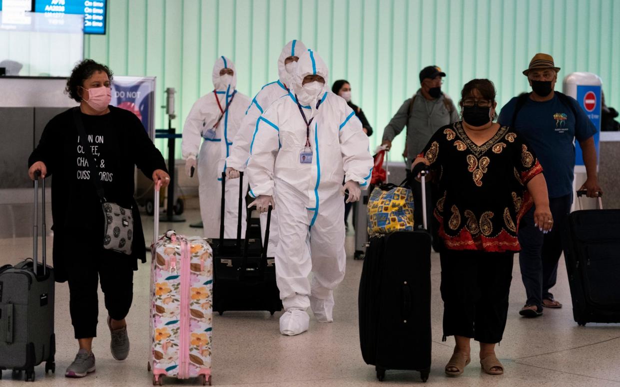 Air China flight crew members in hazmat suits walk through the arrivals area at Los Angeles International Airport on Tuesday, Nov 30 - AP