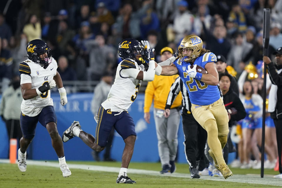 UCLA running back Carsen Ryan, right, stiff-arms California defensive back Nohl Williams as defensive back Patrick McMorris chases during the first half of an NCAA college football game Saturday, Nov. 25, 2023, in Pasadena, Calif. (AP Photo/Ryan Sun)