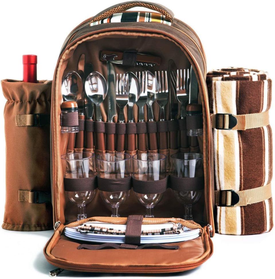 A brown leather picnic bag featuring wine cooler, full cutlery set picnic blanket on a white background