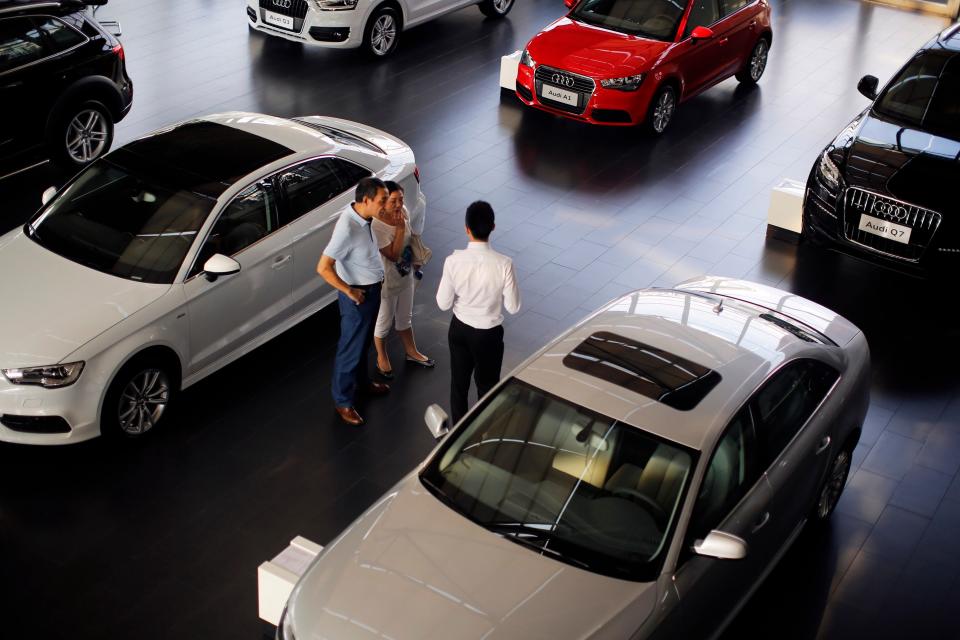 Shoppers stand on the floor of a car dealership.