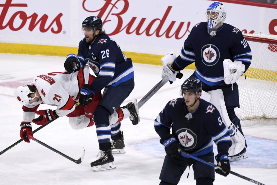 Winnipeg Jets' Blake Wheeler (26) pushes Carolina Hurricanes' Nino Niederreiter (21) in front of goaltender Laurent Brossoit (30) during third period NHL hockey action in Winnipeg, Manitoba on Tuesday Dec. 17, 2019. (Fred Greenslade/The Canadian Press via AP)