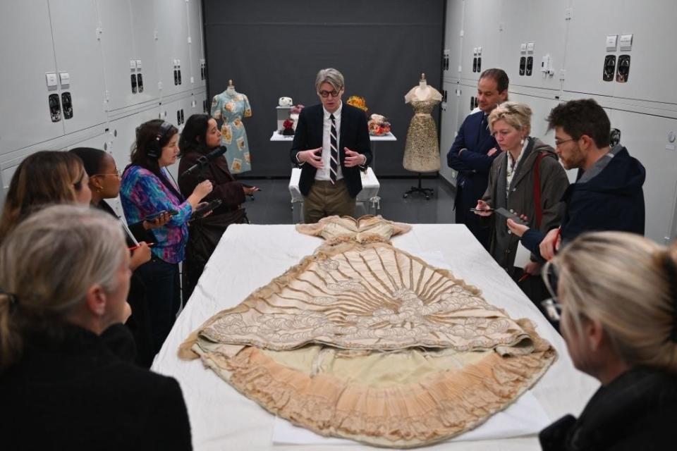 Group listening to a presenter discussing a historic garment laid out on a table
