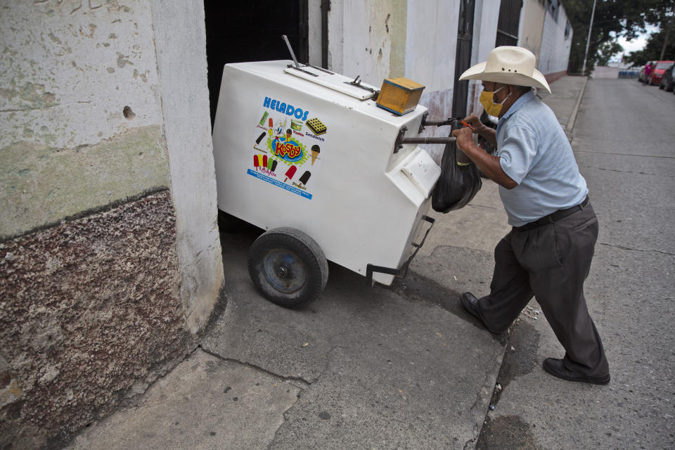 Un hombre retira su carro de la casa en ruinas que solía almacenar los carros de los vendedores de helados y donde viven algunos de ellos durante la pandemia de COVID-19 en la Ciudad de Guatemala, el viernes 29 de mayo de 2020. (AP Foto/Moises Castillo)