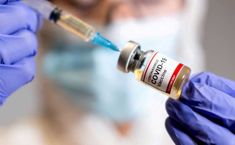 FILE PHOTO: FILE PHOTO: FILE PHOTO: A woman holds a medical syringe and a small bottle labelled "Coronavirus COVID-19 Vaccine