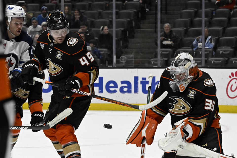 Anaheim Ducks goaltender John Gibson, right, defends with Ducks defenseman Ilya Lyubushkin, center, with Winnipeg Jets center Mason Appleton watching during the first period of an NHL hockey game in Anaheim, Calif., Sunday, Dec. 10, 2023. (AP Photo/Alex Gallardo)