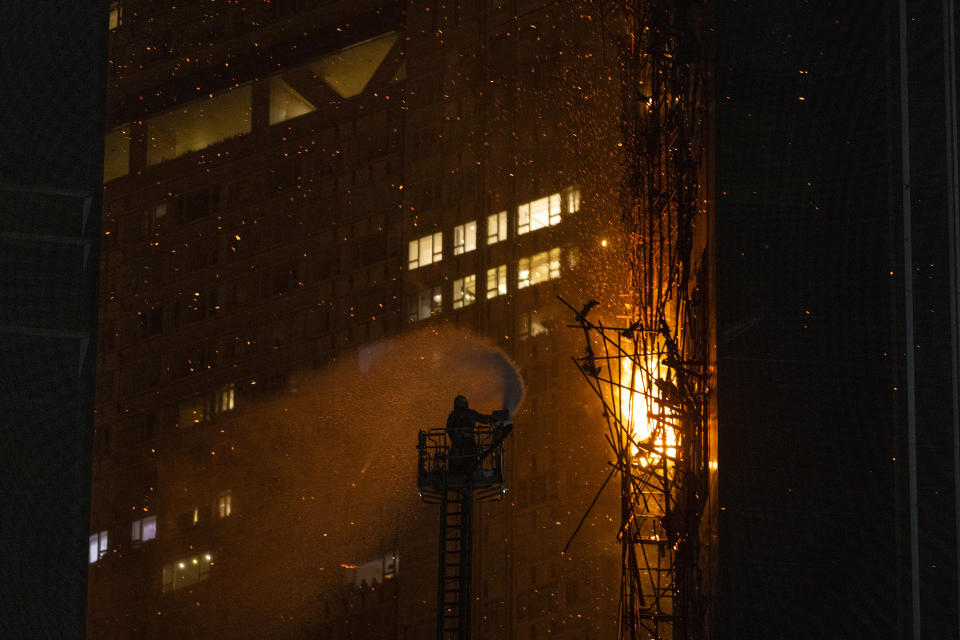 A firefighter sprays water onto a fire in Hong Kong, Friday, March 3, 2023. Hong Kong firefighters are battling the blaze that broke out at a construction site in the city's popular shopping district. (AP Photo/Louise Delmotte)