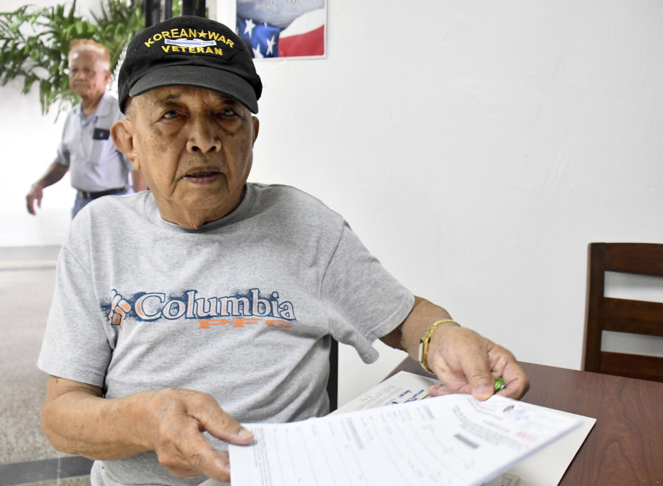 In this Friday, Feb. 7, 2020 photo, Jesus San Nicolas, 86, sits at the Guam war claims office in Tamuning, Guam. The 1941 Japanese invasion of Guam, which happened on the same December day as the attack on Hawaii's Pearl Harbor, set off years of forced labor, internment, torture, rape and beheadings. Now, more than 75 years later, thousands of people on Guam, a U.S. territory, are expecting to get long-awaited compensation for their suffering at the hands of imperial Japan during World War II. (AP Photo/Anita Hofschneider)