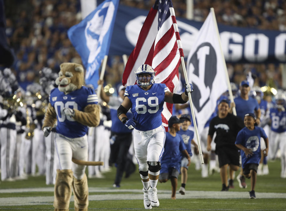 BYU offensive lineman Tristen Hoge (69) brings the American flag onto the field before an NCAA college football game against Utah, Thursday, Aug. 29, 2019, in Provo, Utah. (AP Photo/George Frey)