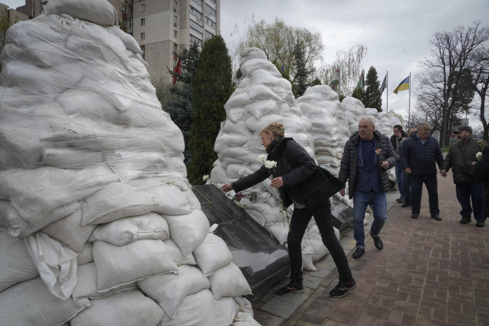 Clean-up operation veterans pay respect to the Chernobyl firefighters to mark the 36th anniversary of the Chernobyl nuclear disaster, at a memorial in the capital Kyiv, Ukraine, Tuesday, April 26, 2022. Firefighters sculptures are covered with bags to protect against the Russian shelling. (AP Photo/Efrem Lukatsky)